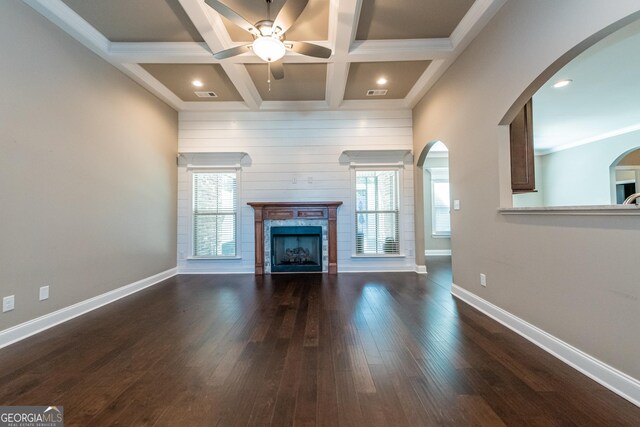 unfurnished living room with coffered ceiling, plenty of natural light, beamed ceiling, and dark hardwood / wood-style floors