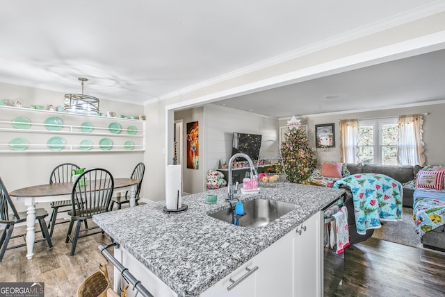 kitchen with white cabinetry, sink, light hardwood / wood-style floors, a kitchen island with sink, and ornamental molding