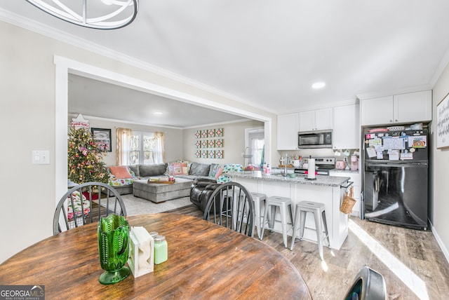 dining area featuring crown molding and light hardwood / wood-style flooring