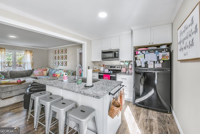 kitchen with light stone countertops, a kitchen breakfast bar, stainless steel appliances, dark wood-type flooring, and white cabinets