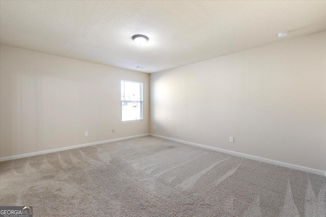 carpeted empty room featuring a textured ceiling