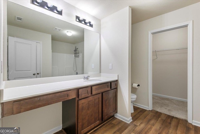 bathroom with a shower, vanity, hardwood / wood-style flooring, and toilet