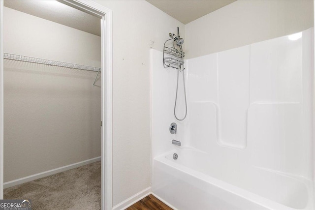 bathroom with hardwood / wood-style floors and washtub / shower combination