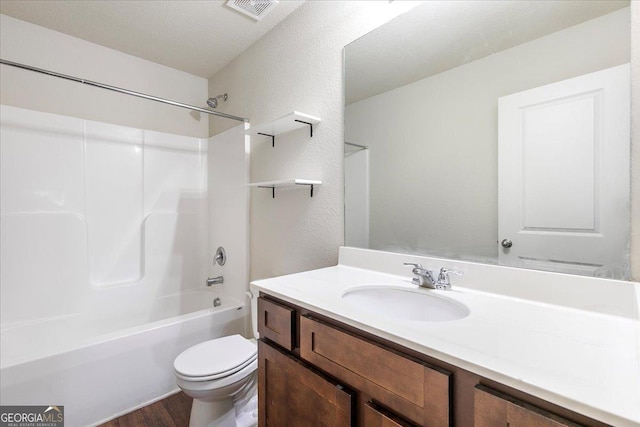 full bathroom with vanity, a textured ceiling, shower / washtub combination, hardwood / wood-style flooring, and toilet