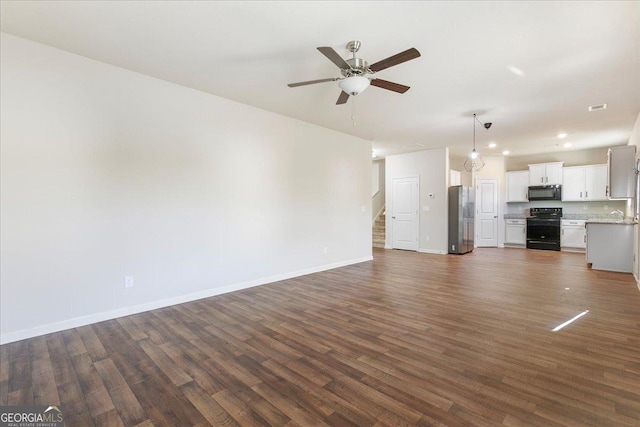 unfurnished living room featuring ceiling fan and dark hardwood / wood-style flooring