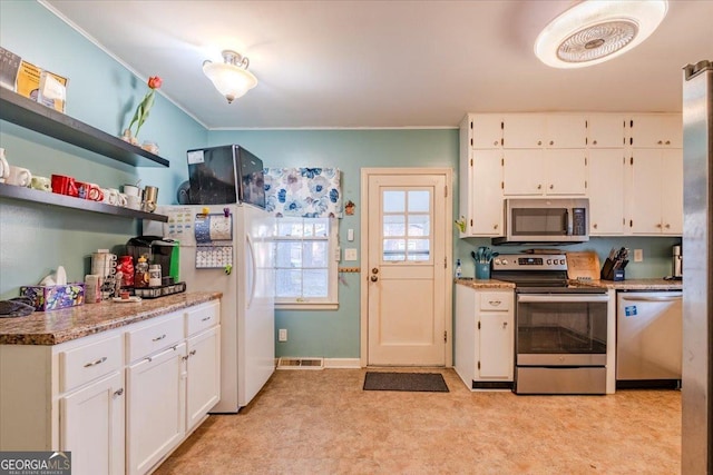 kitchen with light carpet, appliances with stainless steel finishes, light stone counters, ornamental molding, and white cabinets