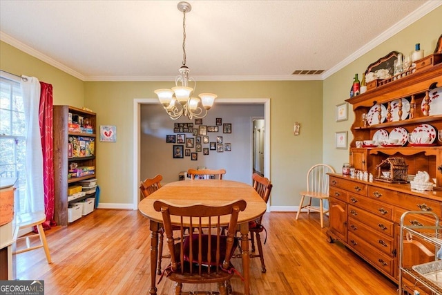 dining room featuring crown molding, light hardwood / wood-style floors, and a notable chandelier