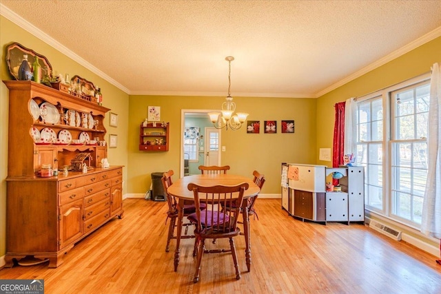 dining area with light hardwood / wood-style floors, a healthy amount of sunlight, ornamental molding, and an inviting chandelier