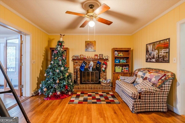 living area featuring wood-type flooring, a textured ceiling, ceiling fan, and ornamental molding