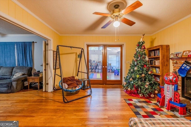 sitting room featuring french doors, a textured ceiling, ceiling fan, crown molding, and hardwood / wood-style floors