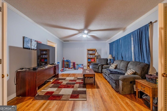 living room featuring a textured ceiling, light wood-type flooring, ceiling fan, and crown molding