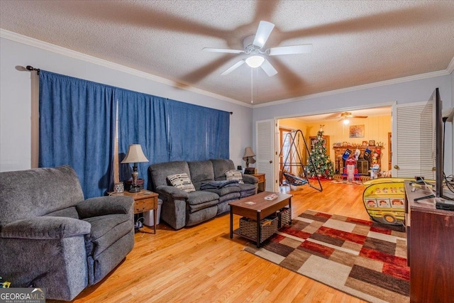 living room with ceiling fan, crown molding, light wood-type flooring, and a textured ceiling