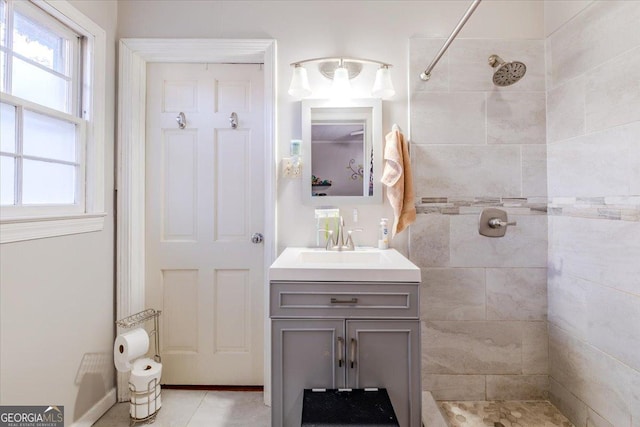 bathroom featuring tile patterned flooring, vanity, and a tile shower