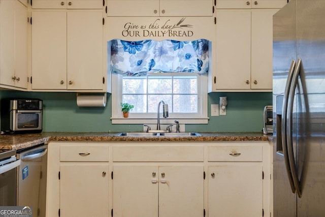 kitchen featuring dark stone countertops, white cabinetry, sink, and appliances with stainless steel finishes