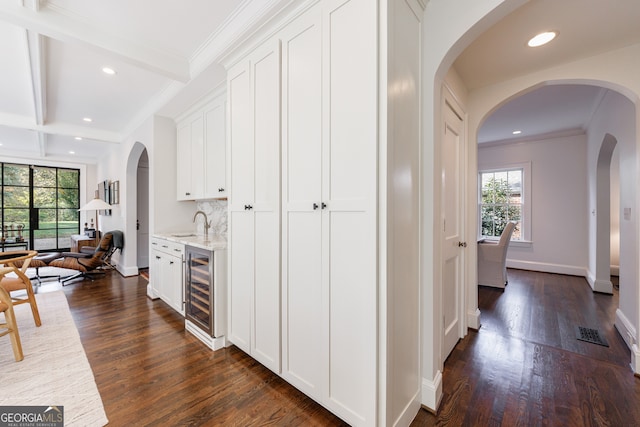 interior space with beverage cooler, ornamental molding, plenty of natural light, and dark wood-type flooring