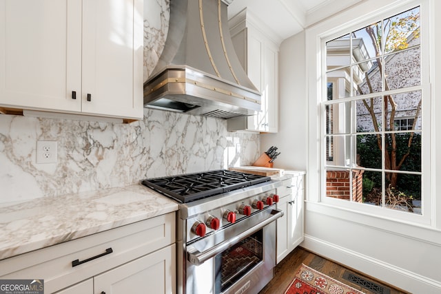 kitchen featuring light stone countertops, designer range, custom range hood, dark hardwood / wood-style floors, and white cabinetry