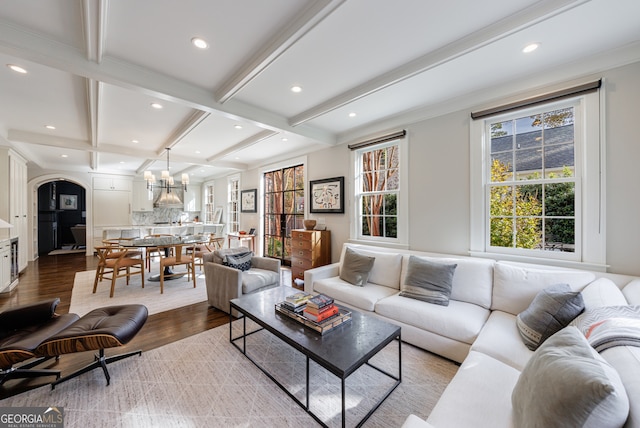 living room with beam ceiling, hardwood / wood-style floors, a notable chandelier, and ornamental molding