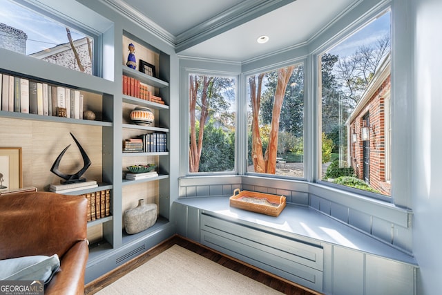 living area with hardwood / wood-style floors, a healthy amount of sunlight, and ornamental molding