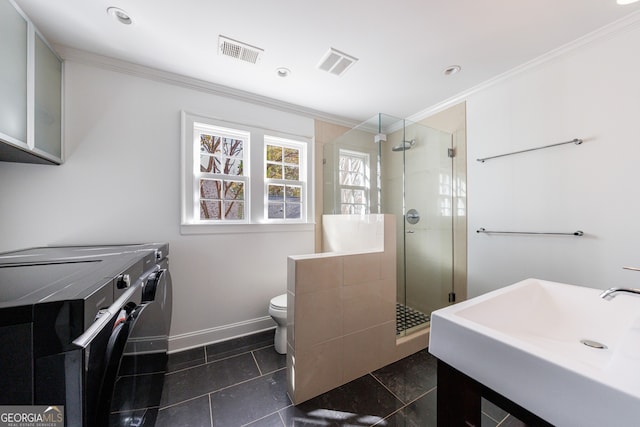 bathroom featuring tile patterned floors, toilet, independent washer and dryer, ornamental molding, and a shower with shower door