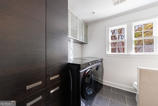 laundry room with independent washer and dryer, dark tile patterned flooring, and crown molding