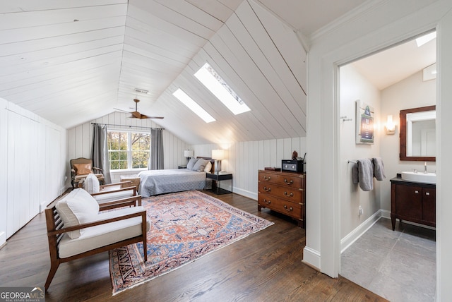 bedroom with ceiling fan, sink, dark hardwood / wood-style flooring, wooden walls, and vaulted ceiling with skylight