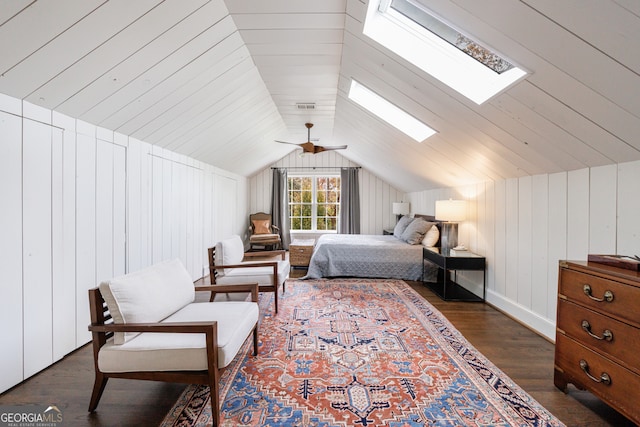 bedroom with dark hardwood / wood-style floors, ceiling fan, wooden walls, and vaulted ceiling with skylight