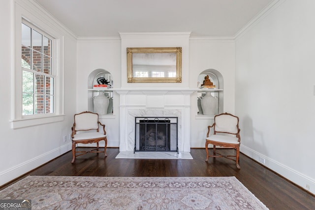 sitting room with crown molding, dark hardwood / wood-style flooring, a high end fireplace, and built in features