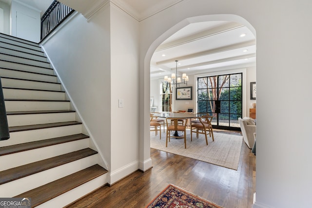 interior space featuring wood-type flooring, ornamental molding, and a notable chandelier