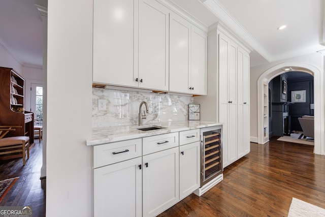 bar featuring white cabinets, sink, light stone countertops, dark hardwood / wood-style flooring, and beverage cooler