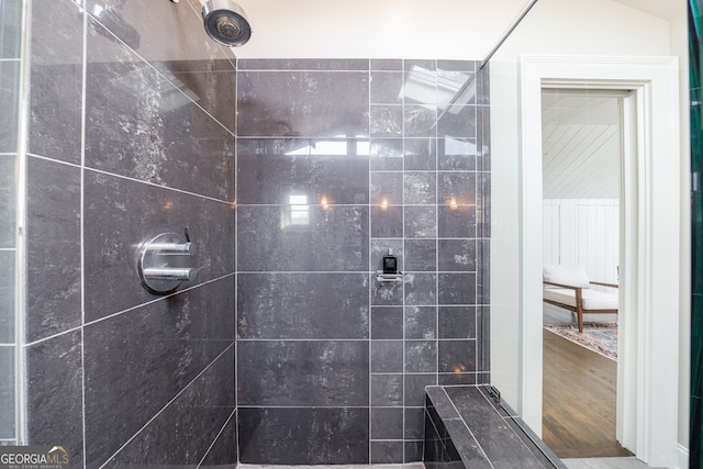 bathroom with wood-type flooring and a tile shower