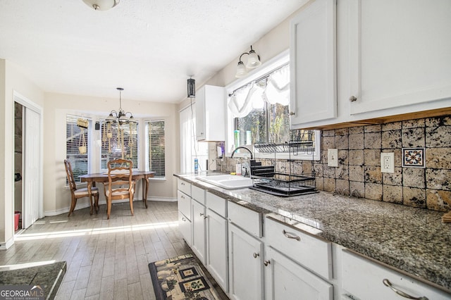 kitchen with decorative backsplash, white cabinetry, light wood-type flooring, and sink