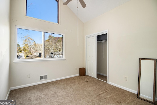 unfurnished bedroom with ceiling fan, a closet, high vaulted ceiling, and light colored carpet