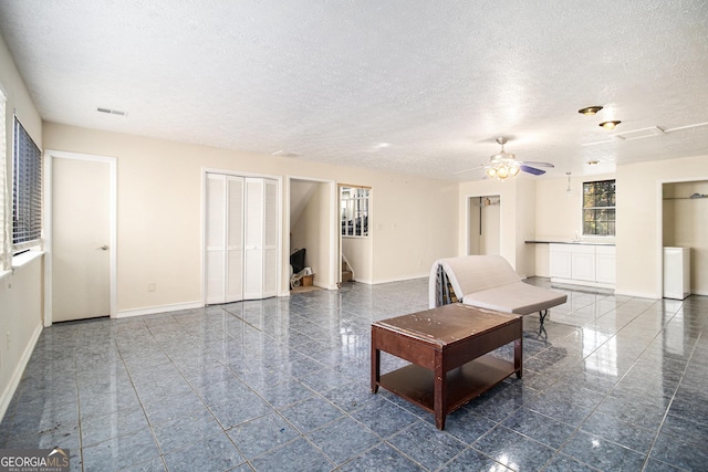 unfurnished living room with a textured ceiling and ceiling fan