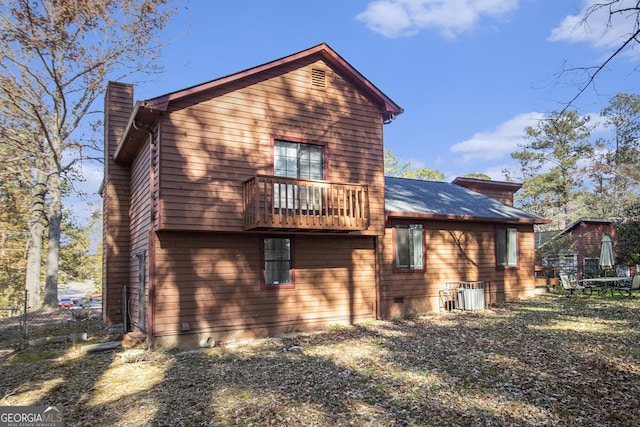 rear view of house with a lawn, a balcony, and cooling unit