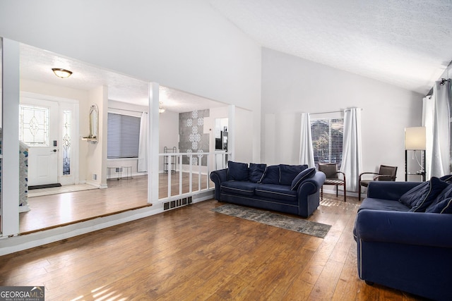 living room with wood-type flooring, a textured ceiling, and high vaulted ceiling