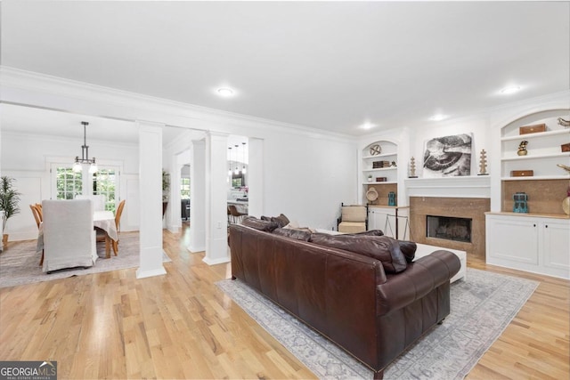 living room featuring built in shelves, light hardwood / wood-style flooring, and ornamental molding