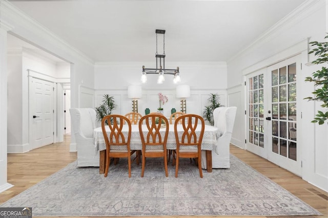 dining area featuring light hardwood / wood-style flooring, an inviting chandelier, french doors, and ornamental molding