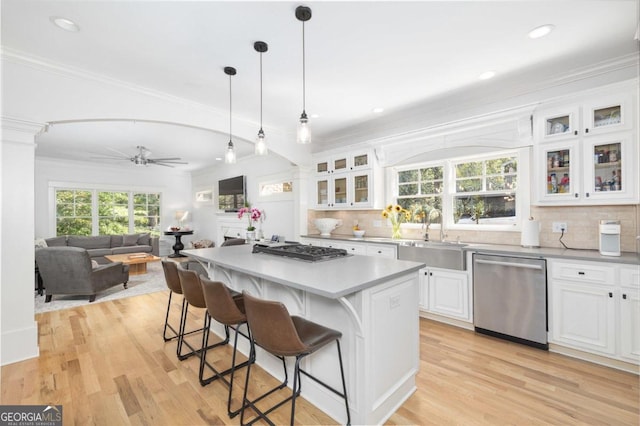 kitchen with sink, light hardwood / wood-style flooring, appliances with stainless steel finishes, a kitchen island, and white cabinetry