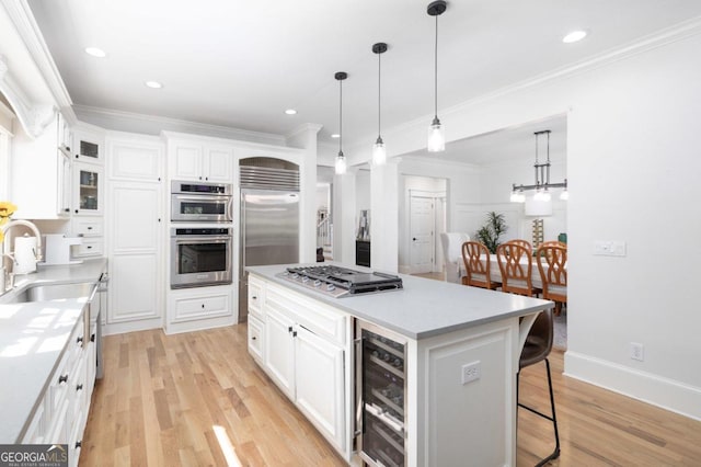 kitchen with a center island, white cabinets, light wood-type flooring, stainless steel appliances, and beverage cooler