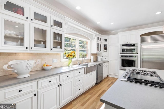 kitchen with white cabinets, appliances with stainless steel finishes, backsplash, and ornamental molding