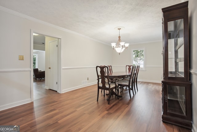 dining space featuring a textured ceiling, ornamental molding, dark hardwood / wood-style floors, and a notable chandelier