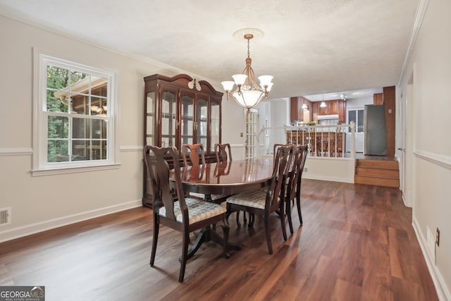 dining space with dark hardwood / wood-style flooring, a chandelier, a textured ceiling, and ornamental molding