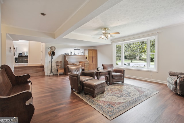 living room with ceiling fan, wood-type flooring, a textured ceiling, and ornamental molding