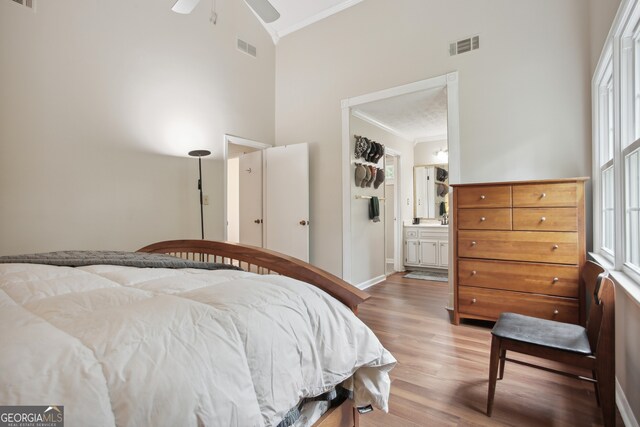 bedroom featuring ensuite bath, ornamental molding, ceiling fan, hardwood / wood-style flooring, and high vaulted ceiling