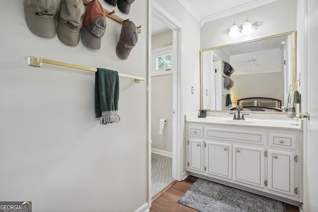 bathroom with ceiling fan, vanity, wood-type flooring, and ornamental molding