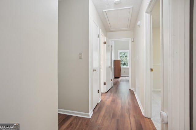 corridor with a textured ceiling and dark wood-type flooring