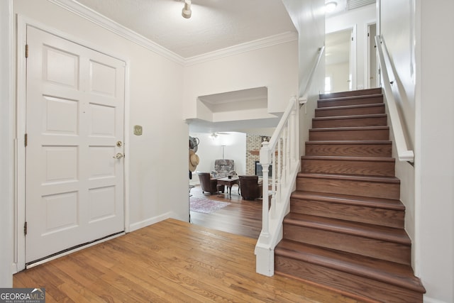 foyer with crown molding, wood-type flooring, and a textured ceiling