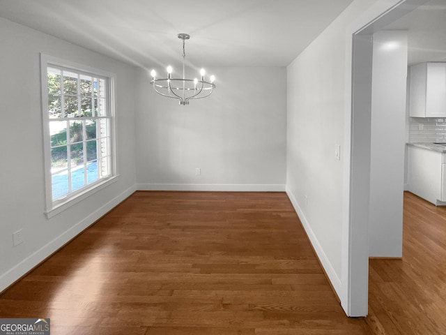 unfurnished dining area featuring a notable chandelier and dark hardwood / wood-style flooring