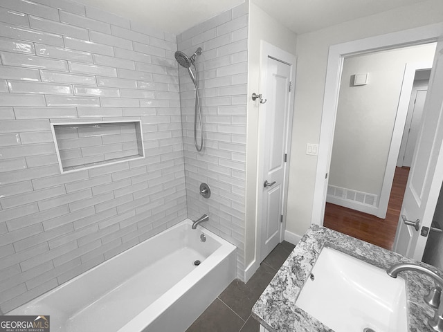 bathroom featuring hardwood / wood-style floors, vanity, and tiled shower / bath