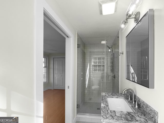 bathroom with vanity, wood-type flooring, and an enclosed shower